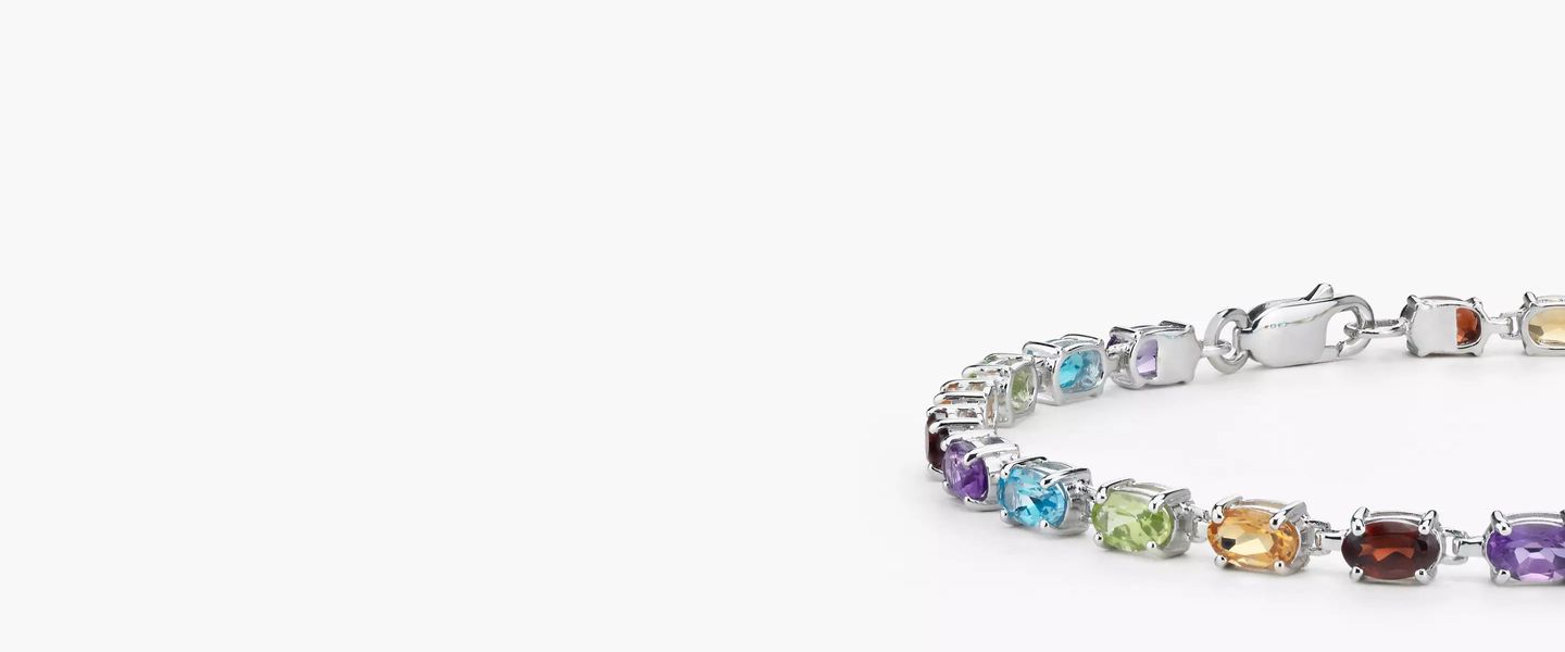 A multi-gemstone bracelet features garnet, citrine, peridot, blue topaz, amethyst, stones arranged in a rainbow pattern framed in sterling silver